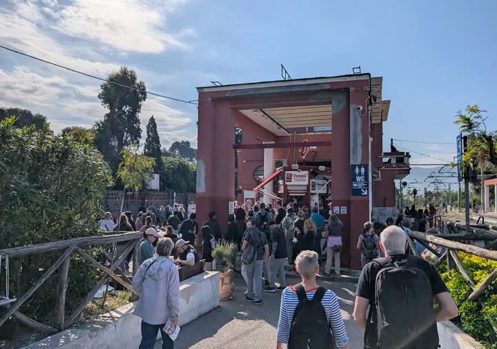 Arriving at Pompeii by train. There are crowds of people.
