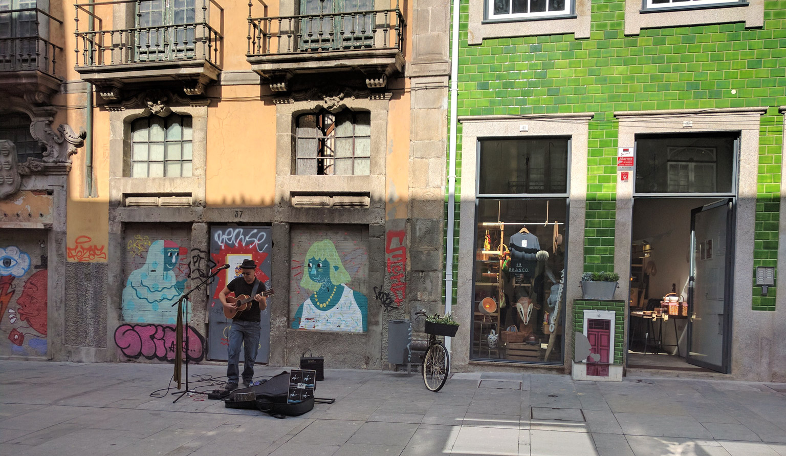 A typical scene on Rua das Flores. A busker plays in front of an abandoned building, while next door is a quirky clothing and accessories shop and AirBnB apartments (including ours)