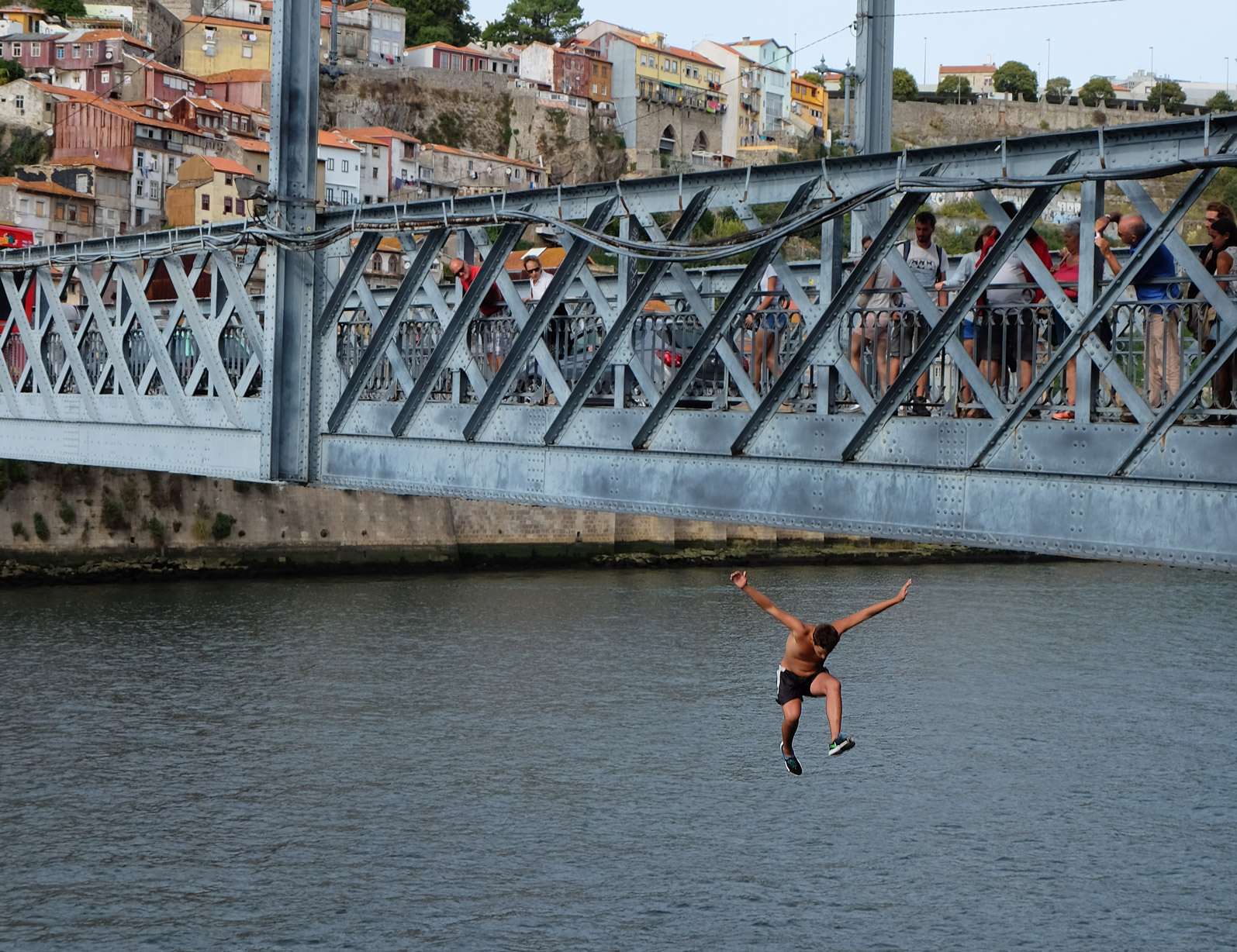 A young lad jumps into the Douro river from the Luís I Bridge