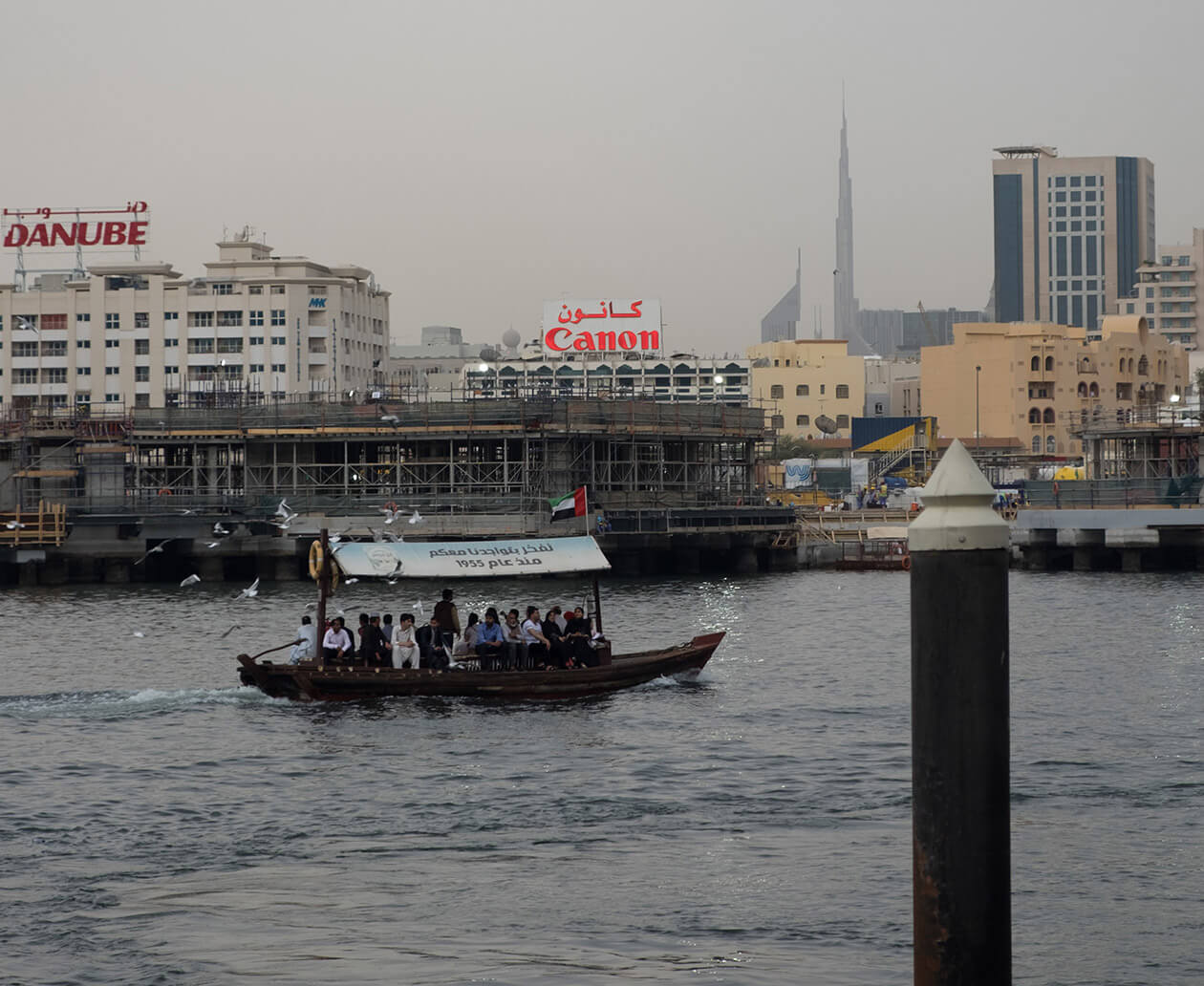 A traditional abra ferry crossing the Dubai Creek with the Burj Khalifa in the distance