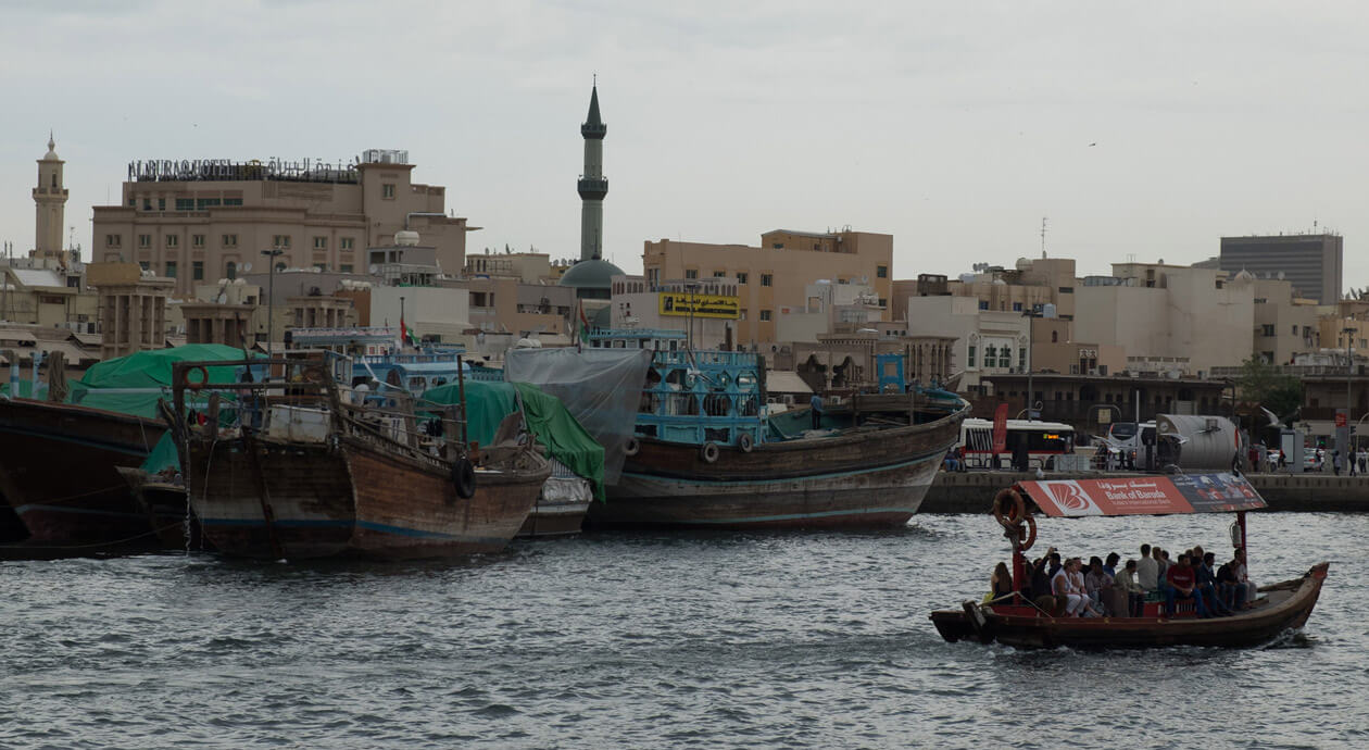 An abra crossing the Dubai Creek in front of dhows