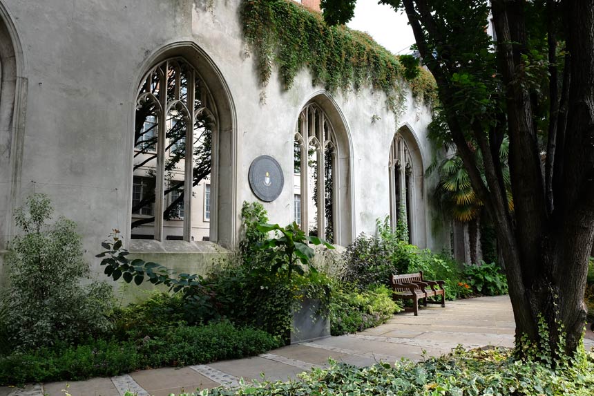 The garden at St Dunstan in the East, an old church which was bombed during the London Blitz. The photo shows the plants, trees and benches inside the church, against a backdrop of the old arched windows. 
