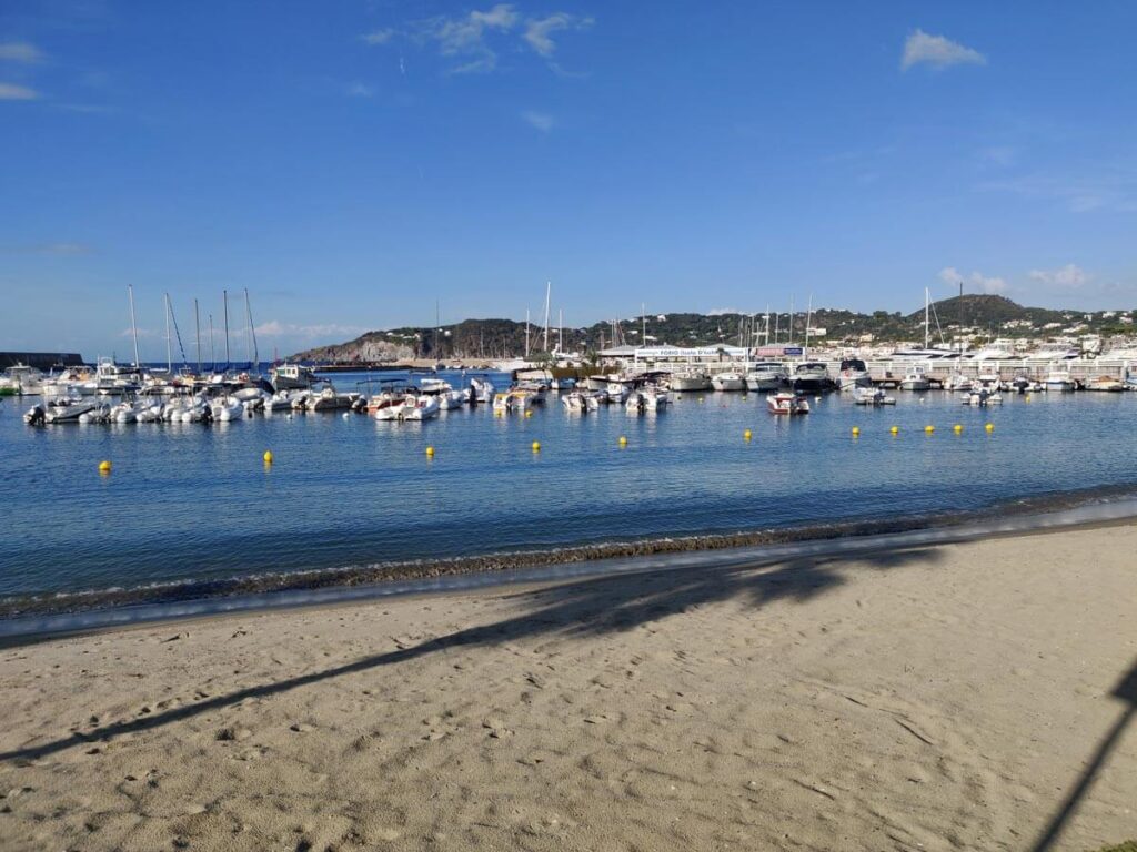 The port in Forio, Ischia. A beach with boats and a body of water.