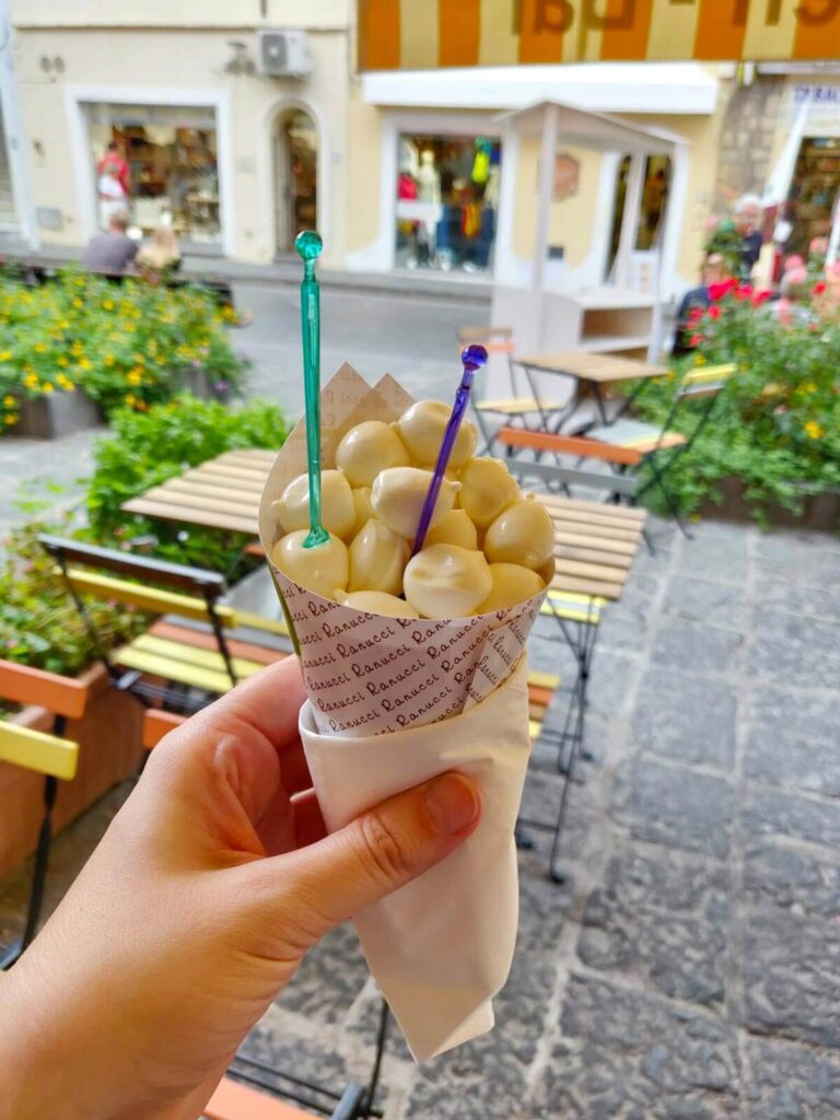 a hand holding a cone with mozzarella balls