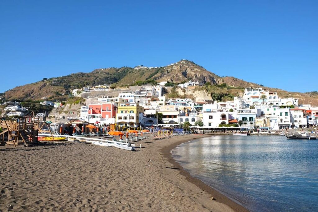 a beach with buildings and a mountain in the background
