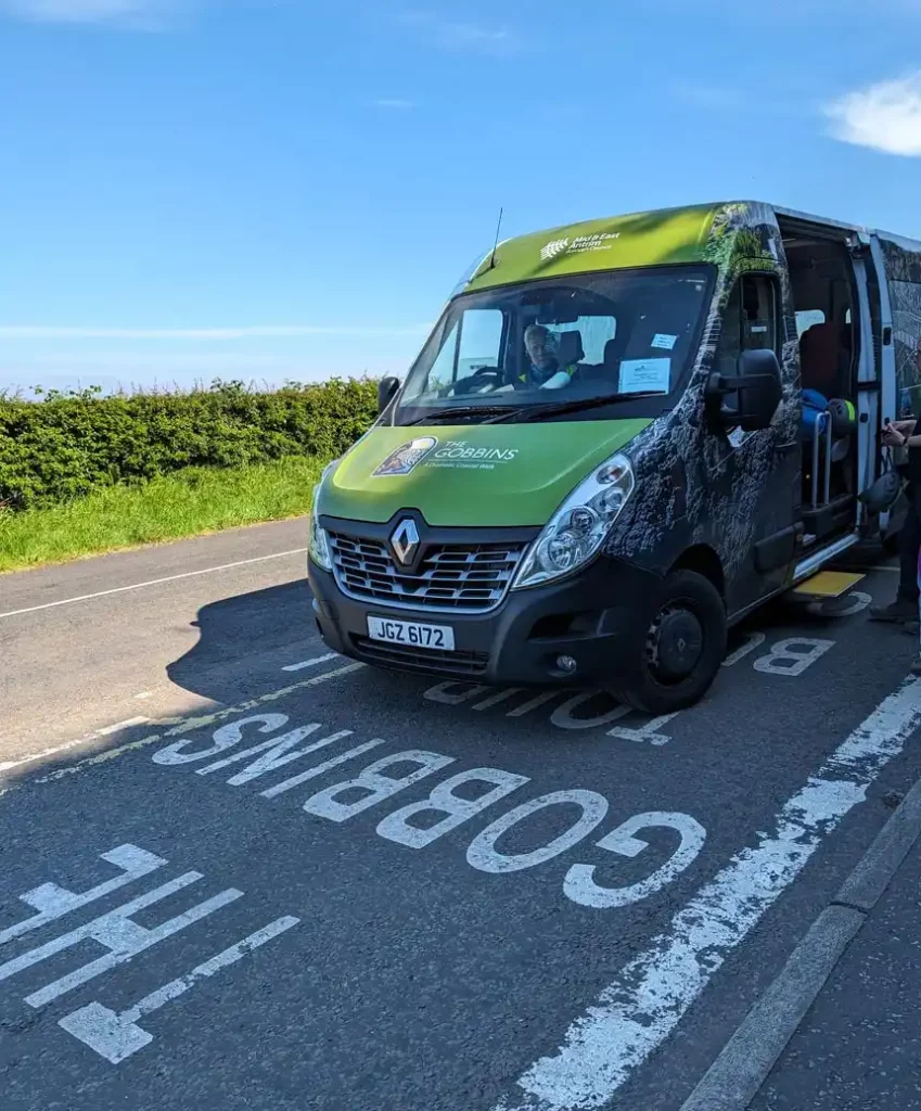 A green minibus parked in a rural layby. "The Gobbins" is painted on the road.