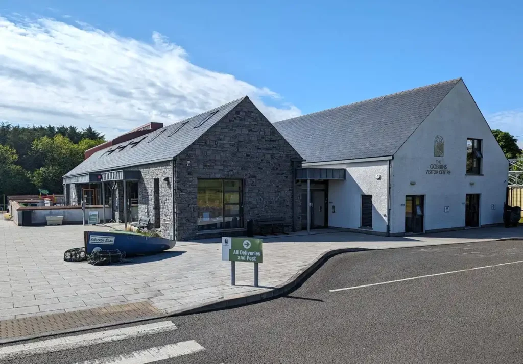 The Gobbins visitor centre. A modern building, with the entrance and cafe at the front. There's a small wooden boat set into the pavement in front of the building. 