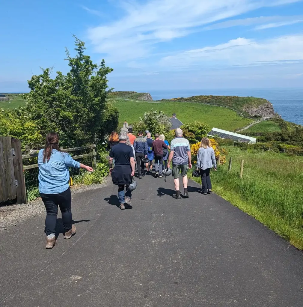 A group of people walking down a country lane towards a sea cliff