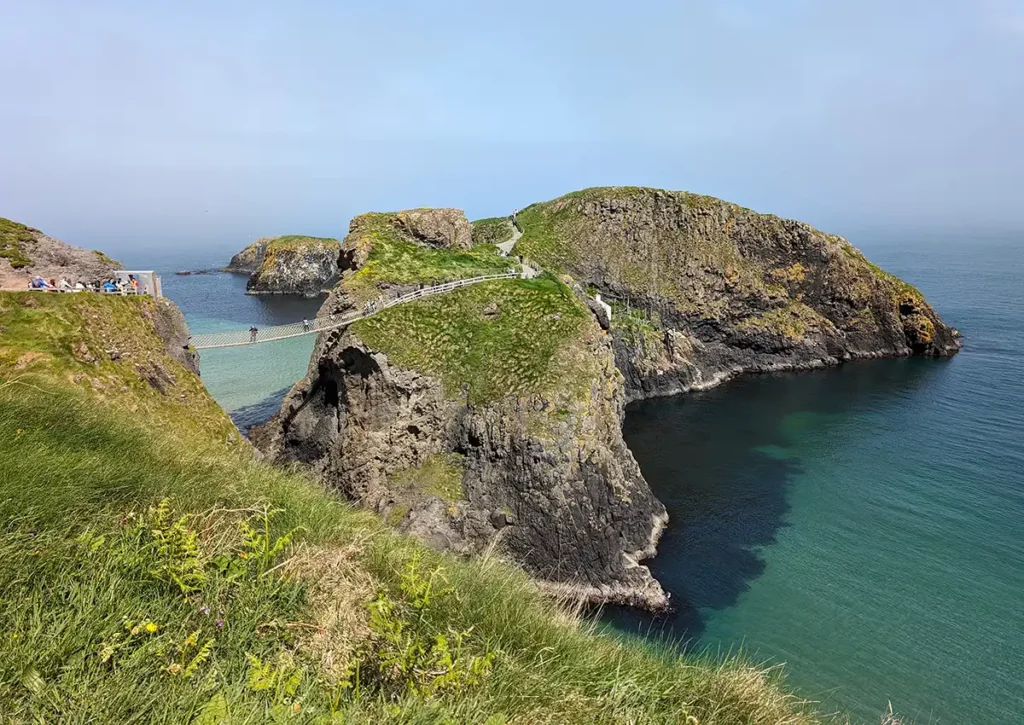 A rope bridge, high above the sea leads across to a rocky island on the Causeway Coast