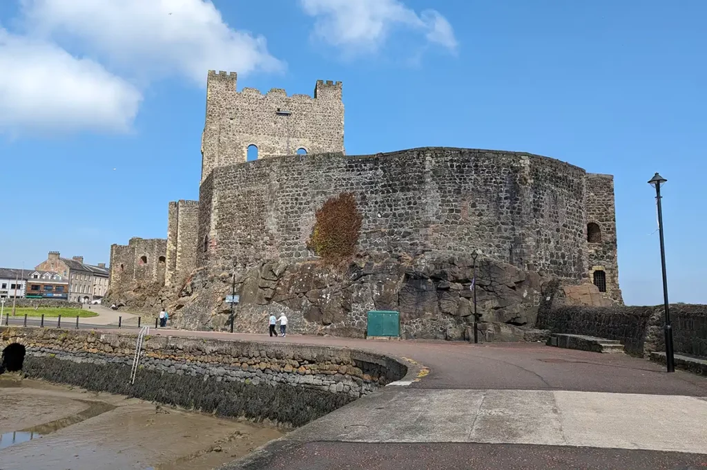 A large stone castle with a square keep on a harbour wall