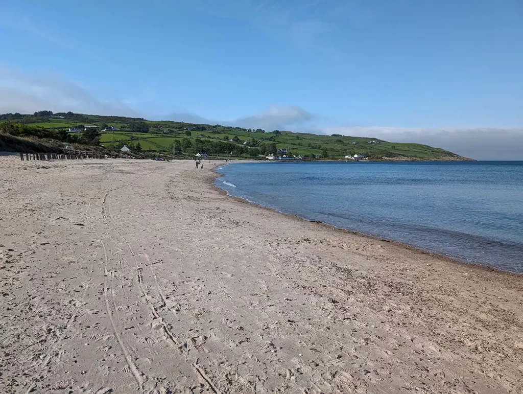 A wide sandy beach with blue sky and sea