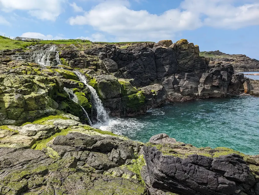 A waterfall flowing down over rocks into the sea