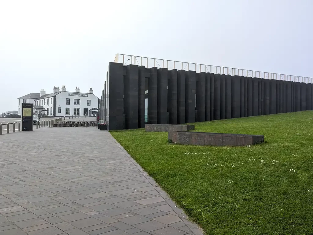 A large modern black building with an older hotel behind