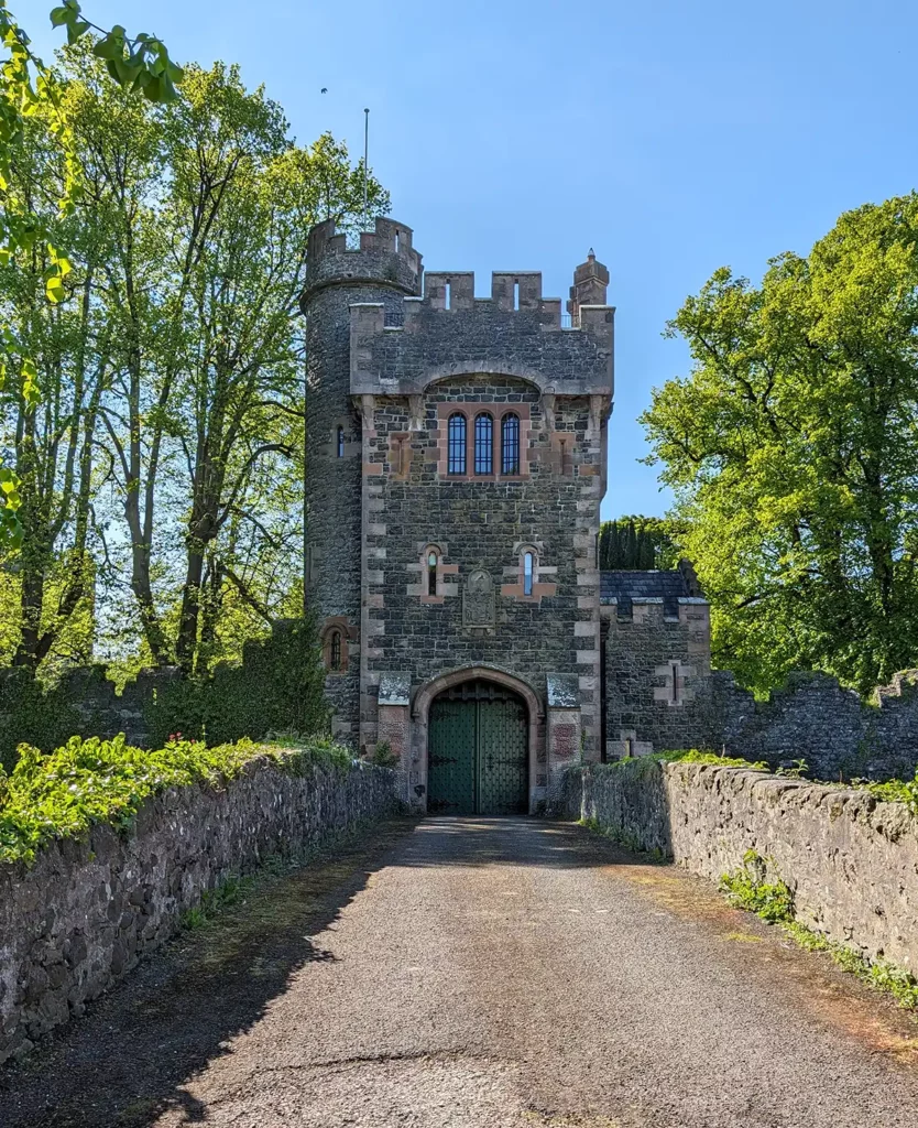 A castle-like tower with an arched doorway and windows at the end of a stone bridge