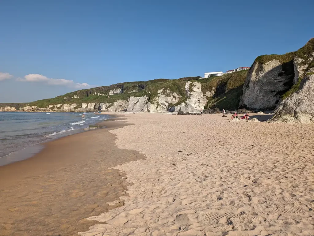 A wide sandy beach with white cliffs and rock formations