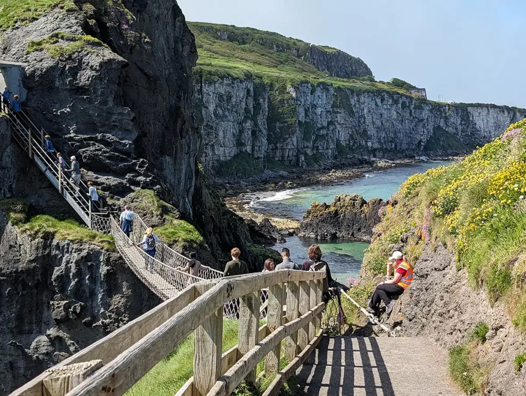 A view of the bridge from the island. A National Trust member of staff in a hi-vis vest is making sure people cross safely.