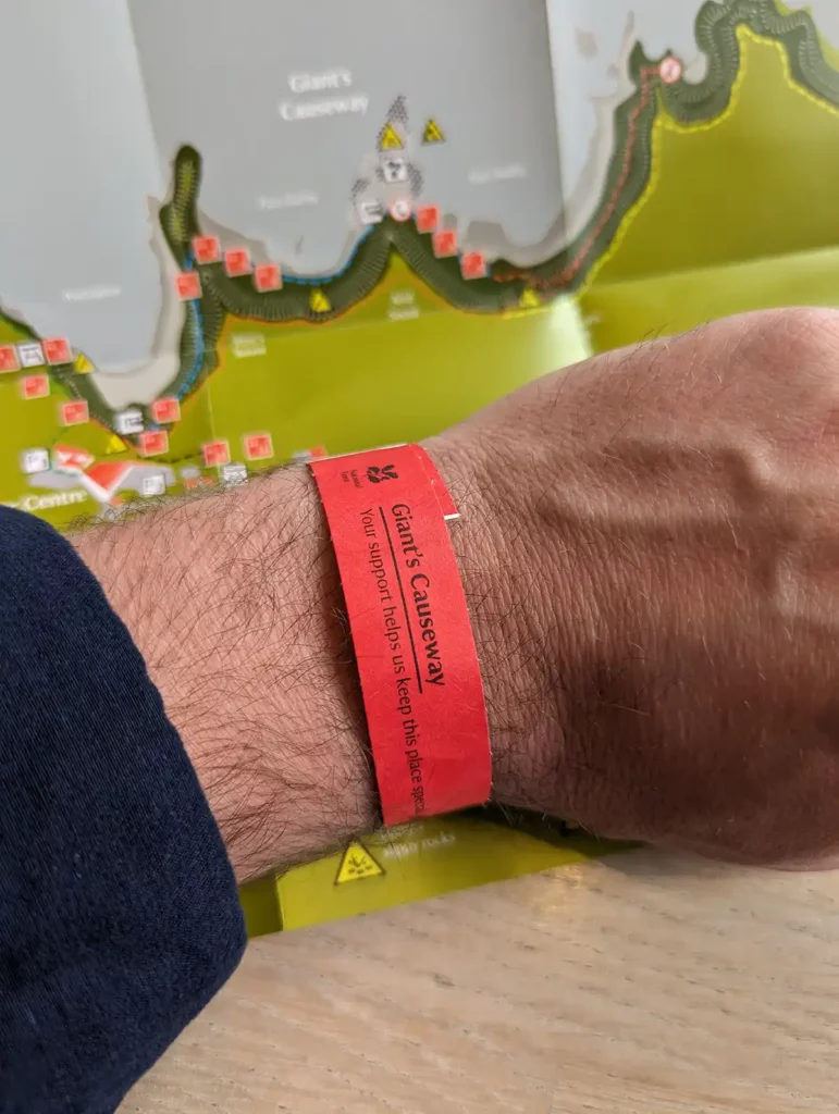 A man's wrist with a Giant's Causeway visitor centre wristband