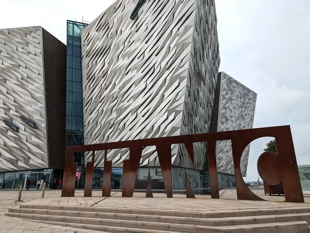 The Titanic Museum in Belfast. A large, modern, angular, silver building, with a sign reading Titanic on the steps in front.