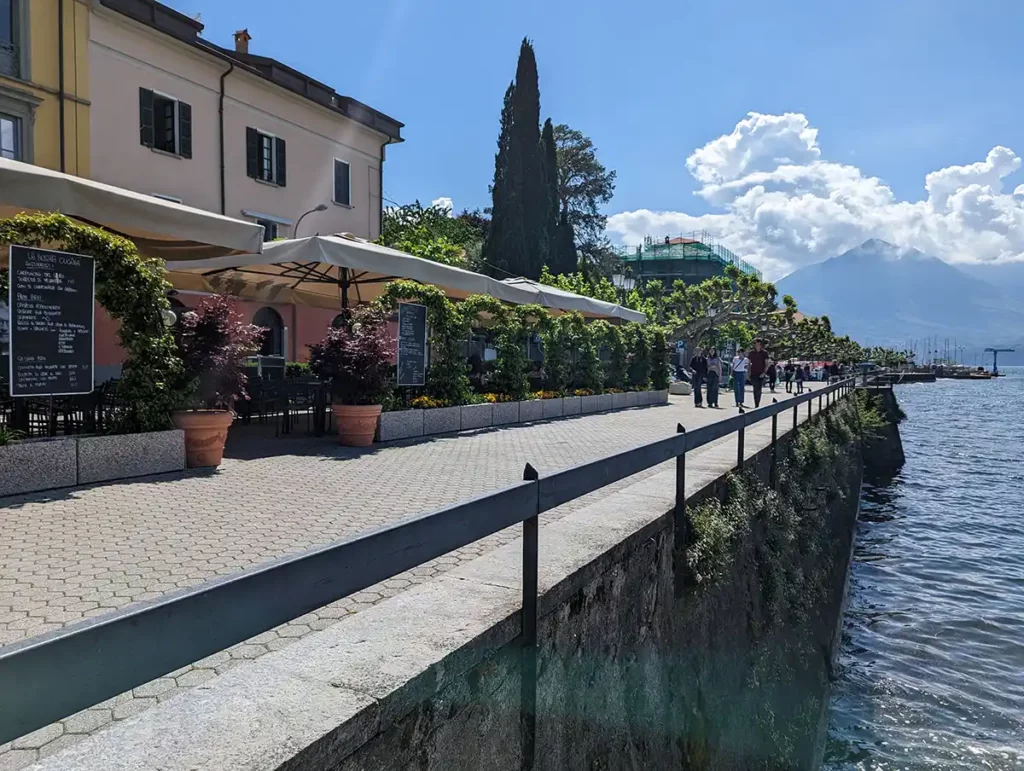 A lakeside promenade on a sunny day, with cafes and restaurants