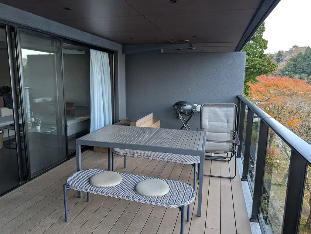 A large balcony with a dining table and barbecue grill