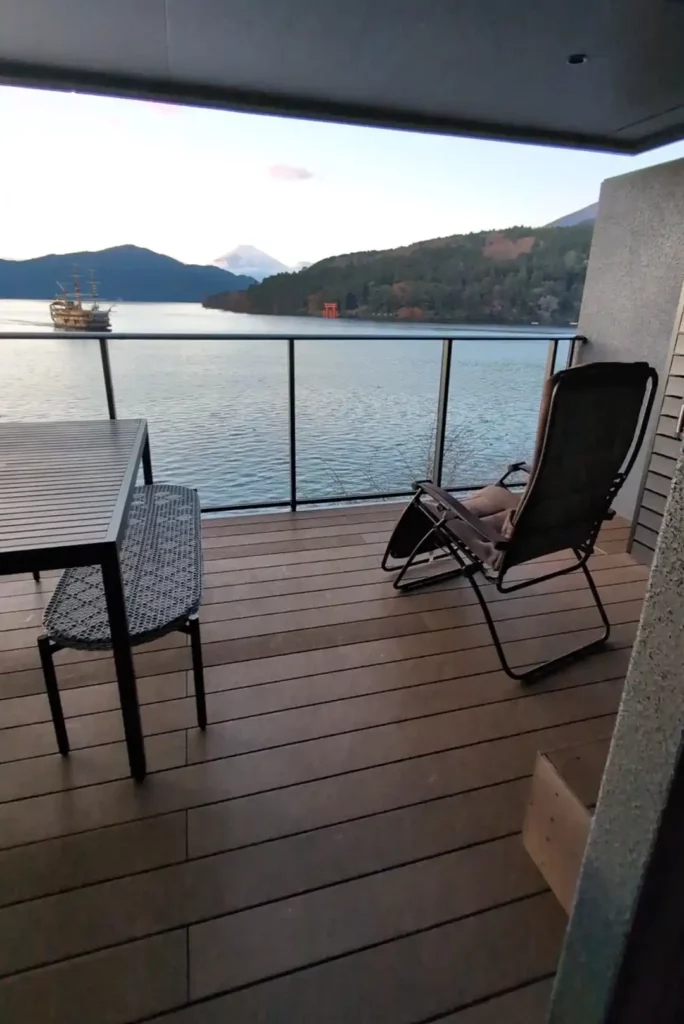 A large balcony with a dining table and recliner. A pirate ship is crossing a lake, and Mount Fuji is visible in the distance. 