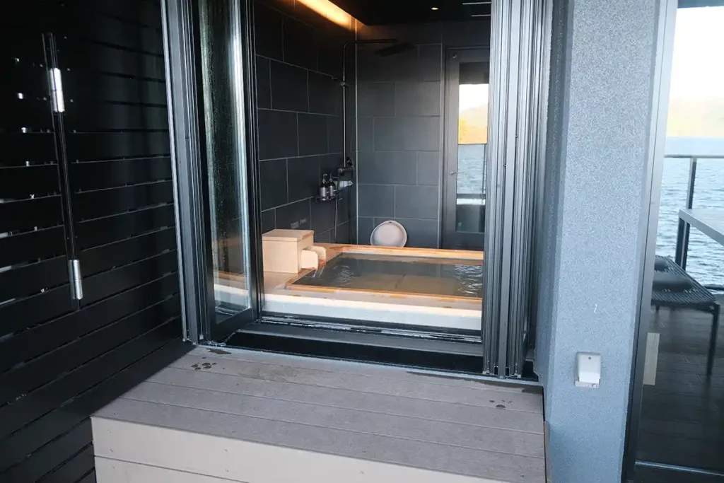 An onsen bath seen from a balcony. The doors to the onsen are open.