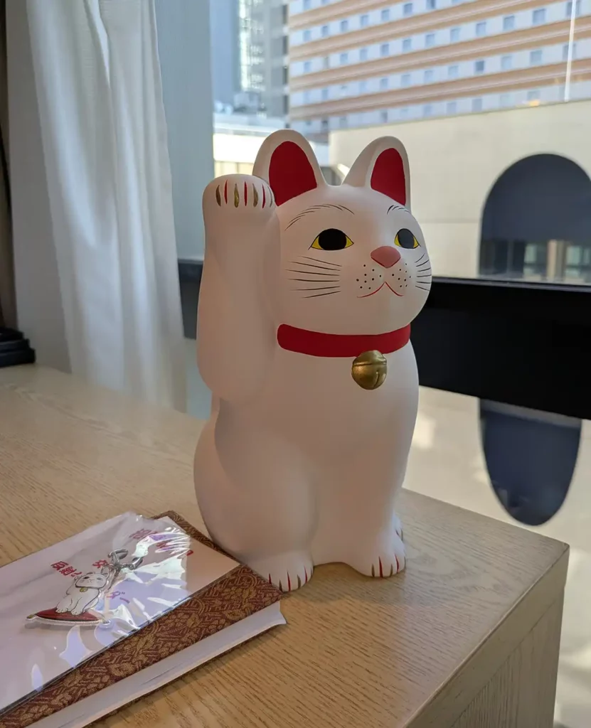 A maneki-neko (beckoning cat) figure on a hotel room desk 