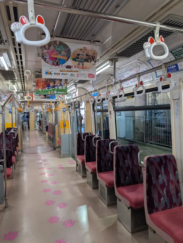 Inside the cat train. There are pink cat paw stickers on the floor and the grab handles are shaped like the head and paw of a beckoning cat.