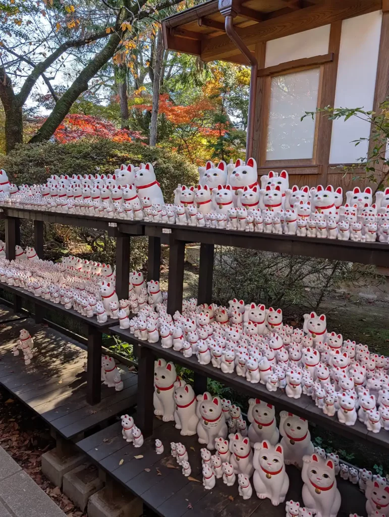 Lucky beckoning cat figures around the edges of a shrine at Gōtokuji Temple