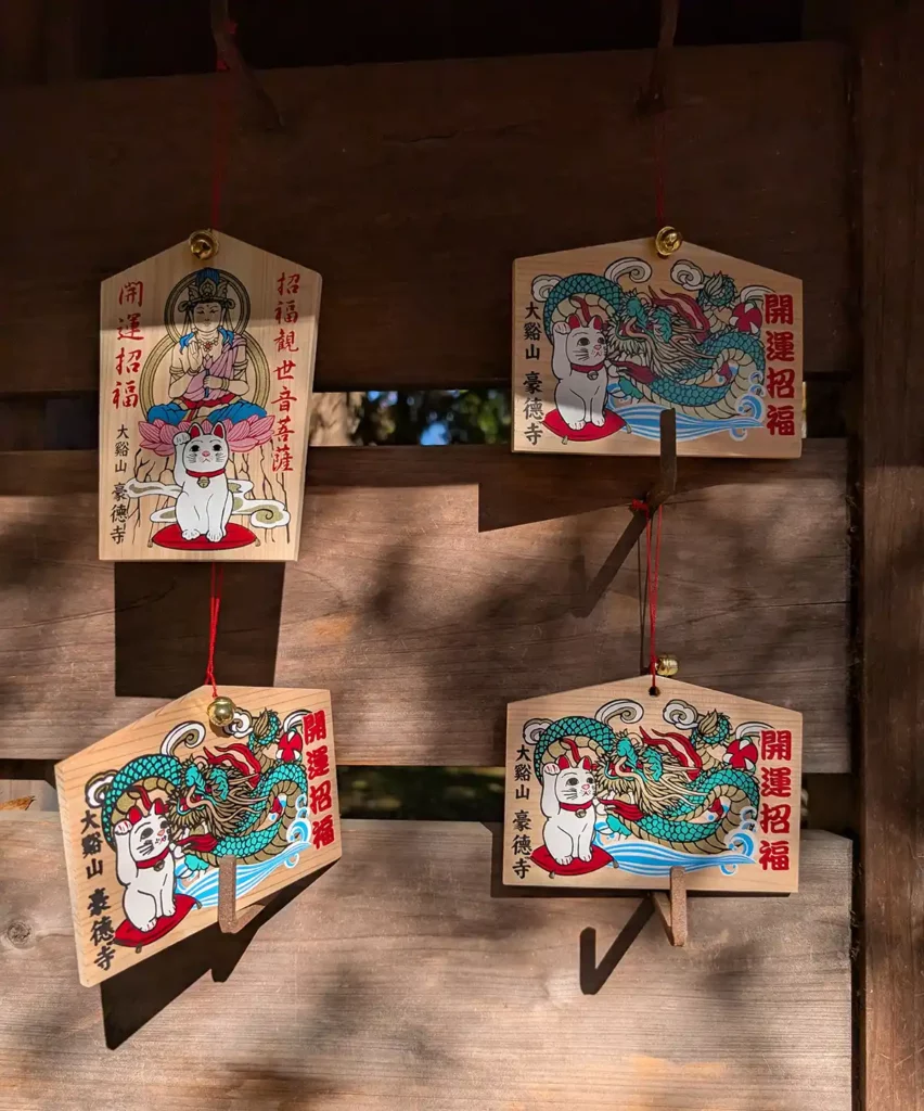 Wooden prayer plaques with cat pictures on the front, hung up on pegs