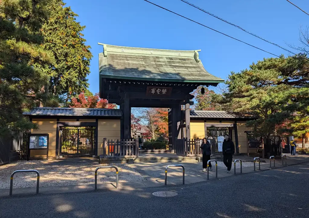 A large, dark wood gate at the entrance to the temple