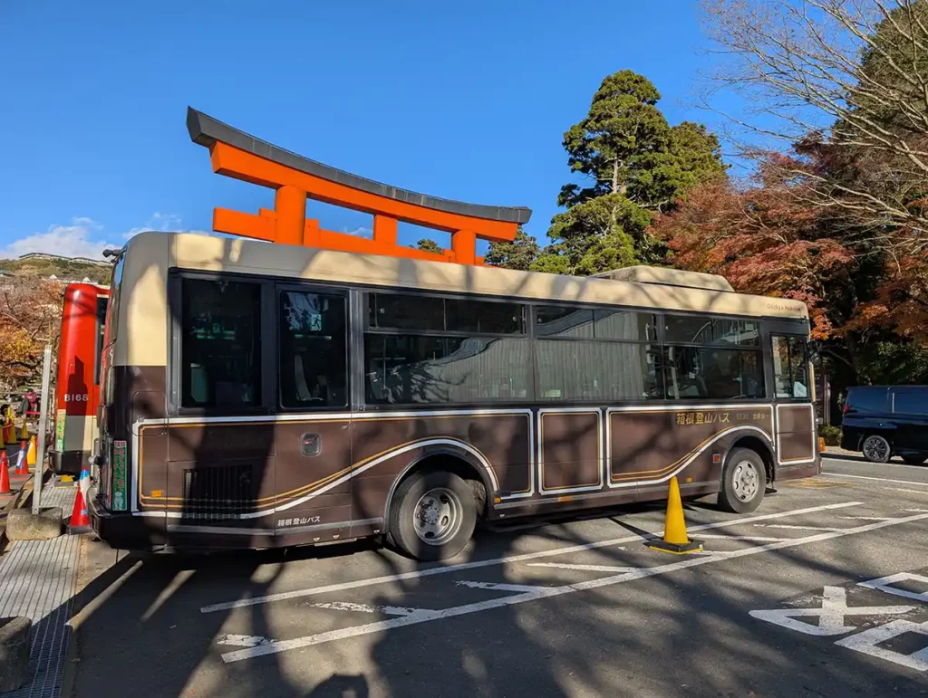 A brown bus at a bus stop, in front of a red Torii gate in Japan