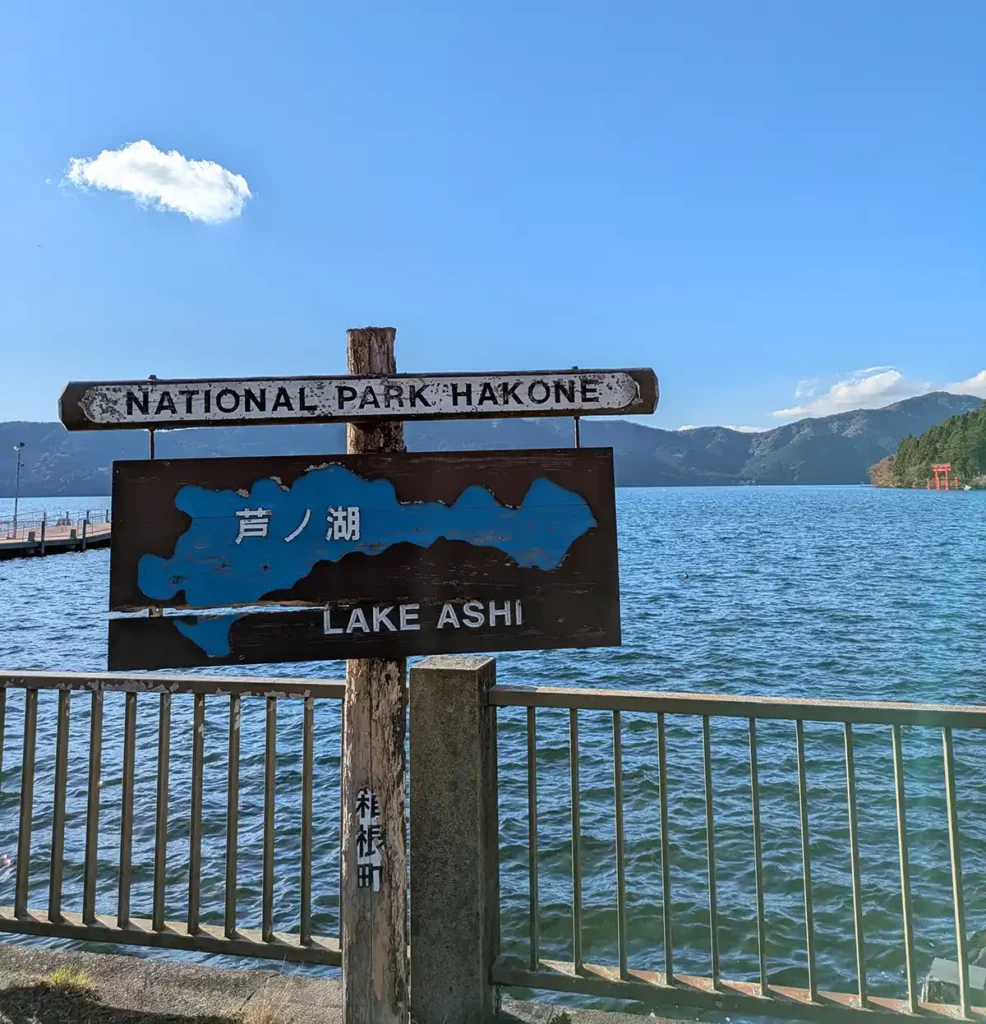 A sign next to a lake reading National Park Hakone, with another underneath reading Lake Ashi