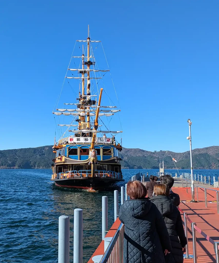 A cruise boat decorated as a pirate ship arriving at a dock, with people waiting to board