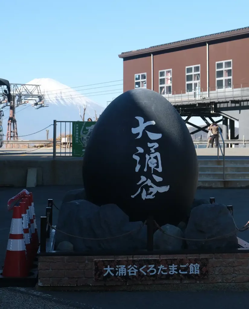 A sculpture shaped like a black egg with Japanese writing in white on the front