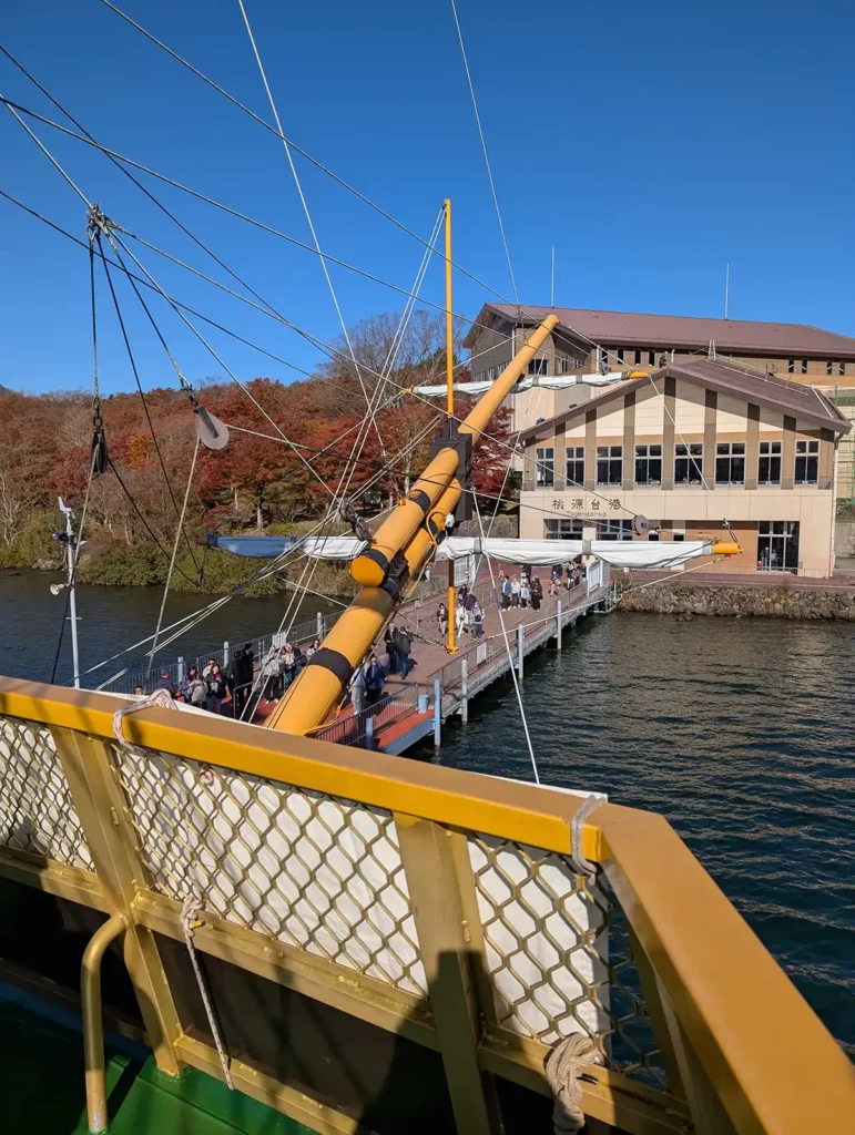 A pirate ship arriving at a dock. There's a low visitor centre building, with a taller one behind with the ropeway station.