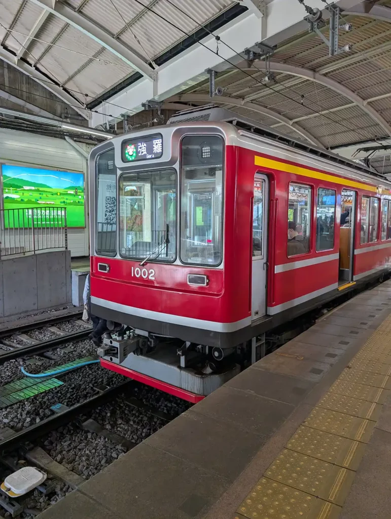 A red train at Hakone-Yumoto station getting ready to set off for Gora