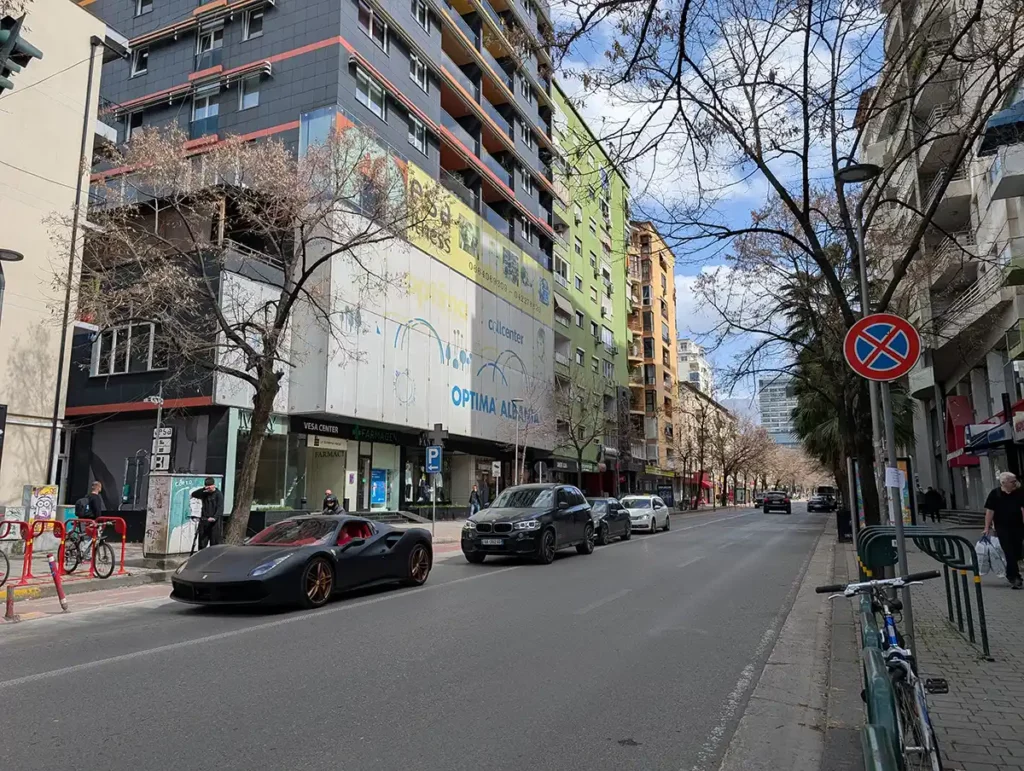 A street in the Blloku neighbourhood. There are two expensive cars on the street. 