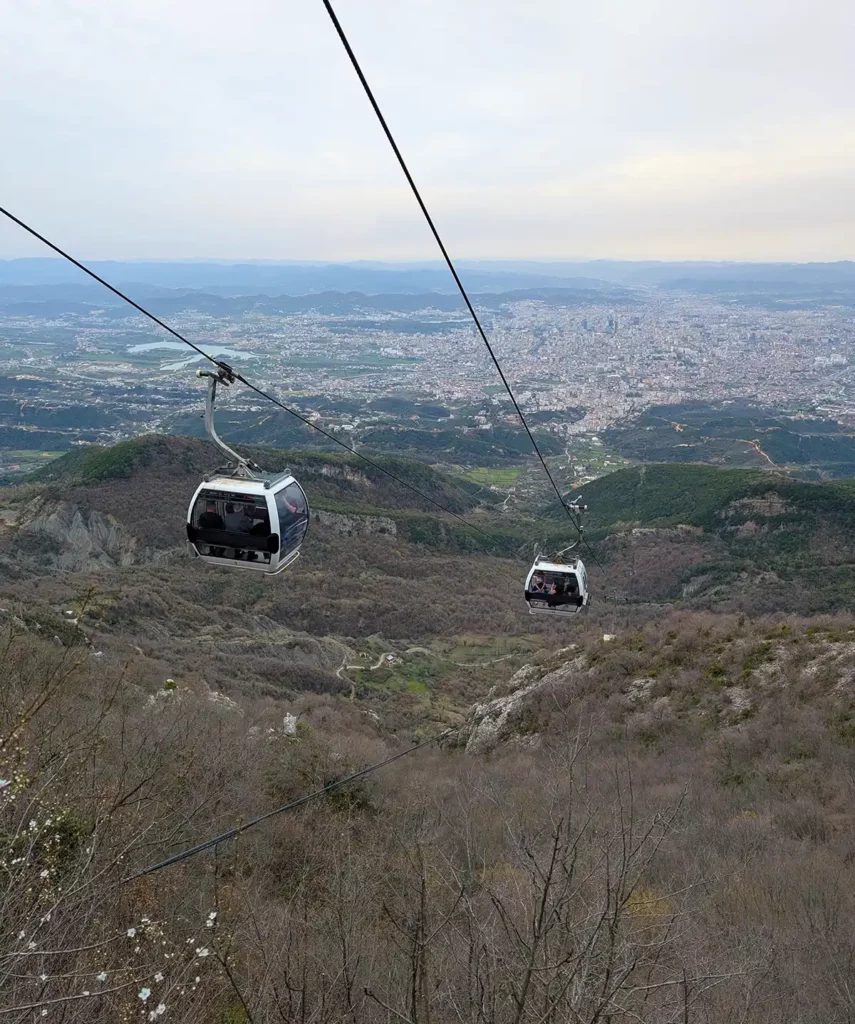 A cable car going up a mountain, with a city far below