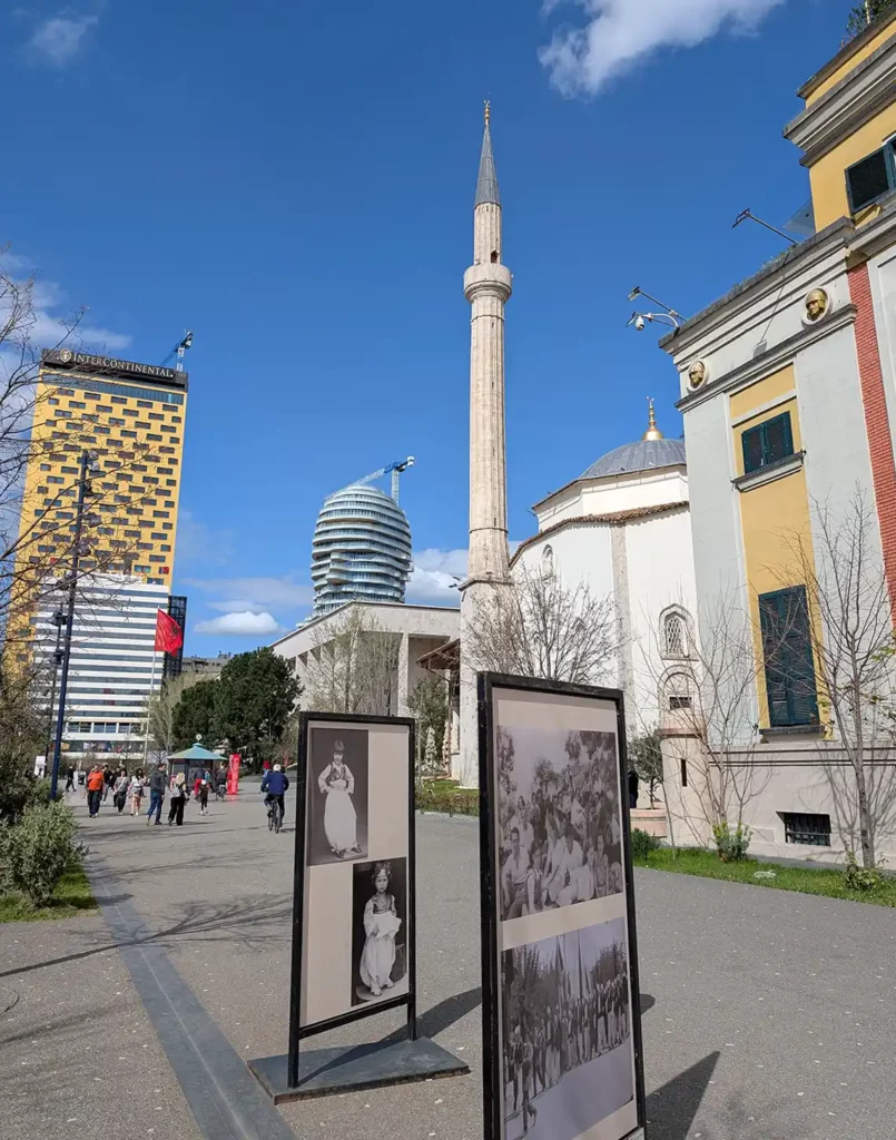 A view of the varied buildings around Tirana's Skanderbeg Square; a Communist-era hotel, a brand new skyscraper in the shape of a man's head, an 18th-century mosque and a 1920s government building 