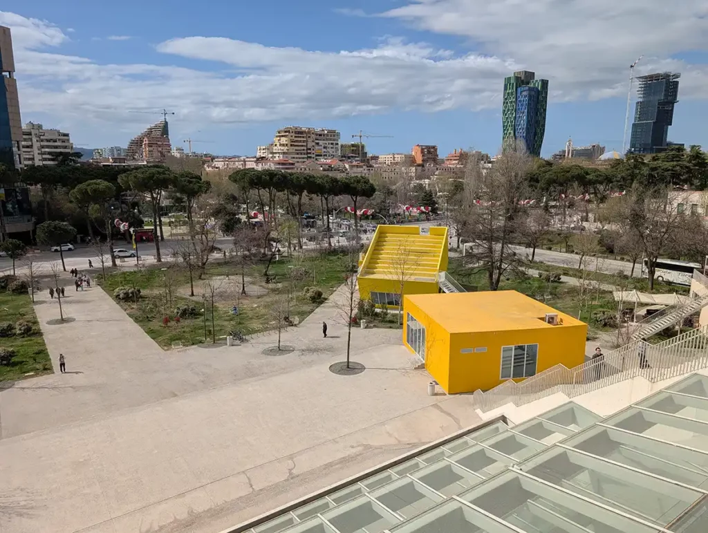 A view of Tirana from the top of the Pyramid. There are two yellow blocks containing a shop and cinema at the bottom.